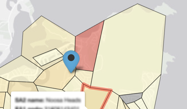 In the background, a very light grey map of Peregian Springs in Queensland, with the ocean in a darker grey.
              In the foreground on land, there are shapes with black borders in shades of yellow, orange and red, indicating Statistical Areas 1. A blue pin icon with a black dot inside indicates an evacuation area. 
              In the bottom left-to-center, a white caption box has some blurred, illegible text in it.